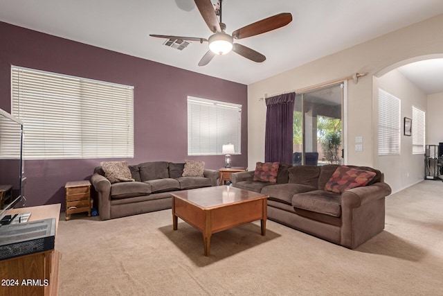 carpeted living room featuring arched walkways, visible vents, and ceiling fan