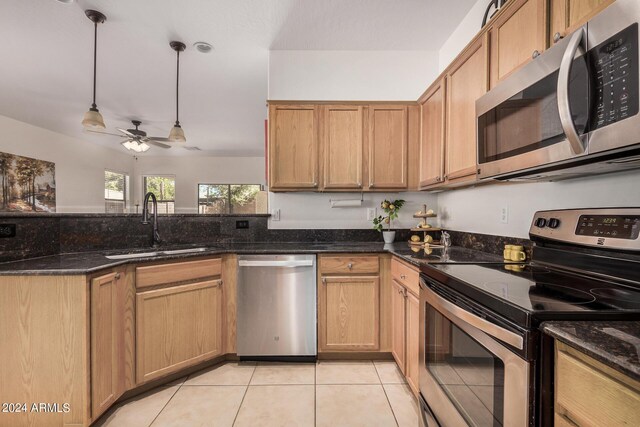 kitchen with ceiling fan, sink, dark stone countertops, pendant lighting, and appliances with stainless steel finishes