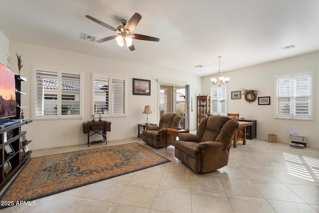 tiled living area with ceiling fan with notable chandelier, visible vents, and baseboards