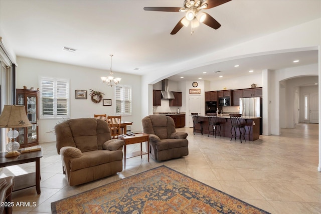 living room featuring light tile patterned floors, recessed lighting, visible vents, arched walkways, and ceiling fan with notable chandelier