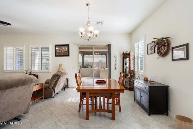 dining space featuring an inviting chandelier, visible vents, and light tile patterned flooring