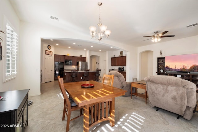 dining room with ceiling fan with notable chandelier, arched walkways, visible vents, and light tile patterned flooring