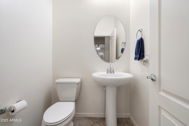 half bathroom with tile patterned flooring, a sink, toilet, and baseboards