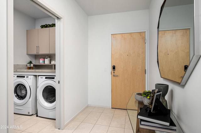 laundry area with light tile patterned floors, baseboards, cabinet space, and washing machine and clothes dryer