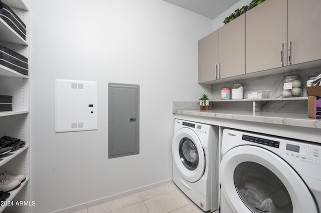 clothes washing area with light tile patterned floors, baseboards, washer and dryer, cabinet space, and electric panel