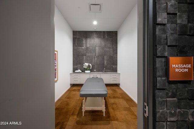 home office with an accent wall, a sink, and tile walls