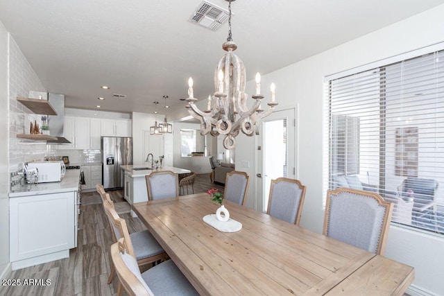 dining space with sink, light hardwood / wood-style flooring, and a chandelier