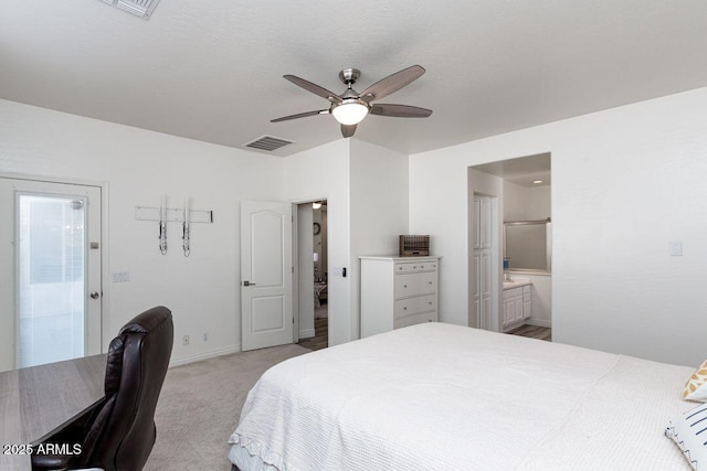 bedroom with ceiling fan, ensuite bath, and light colored carpet