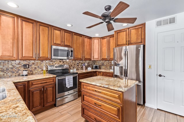 kitchen with ceiling fan, backsplash, light stone counters, and stainless steel appliances