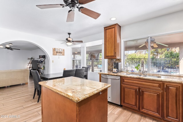 kitchen featuring light stone countertops, sink, stainless steel dishwasher, and a kitchen island