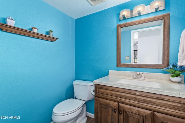 bathroom with toilet, vanity, and a textured ceiling