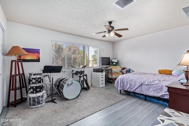 bedroom with ceiling fan, light wood-type flooring, and a textured ceiling