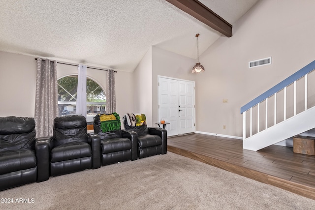 carpeted home theater with vaulted ceiling with beams and a textured ceiling