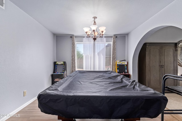 bedroom with wood-type flooring, pool table, a chandelier, and a textured ceiling