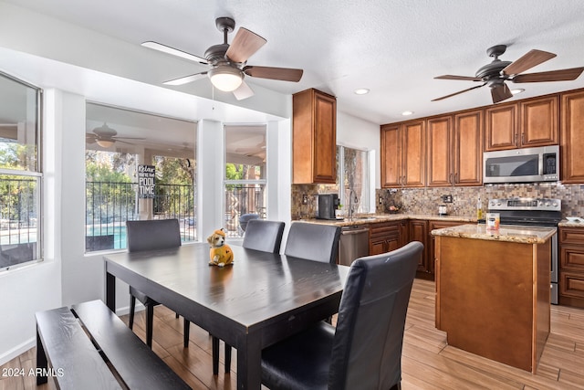 kitchen featuring appliances with stainless steel finishes, a healthy amount of sunlight, light stone counters, and a kitchen island