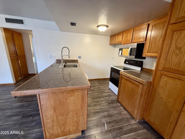 kitchen with backsplash, dark hardwood / wood-style floors, electric range oven, sink, and an island with sink