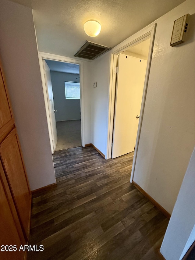 hallway featuring a textured ceiling and dark wood-type flooring