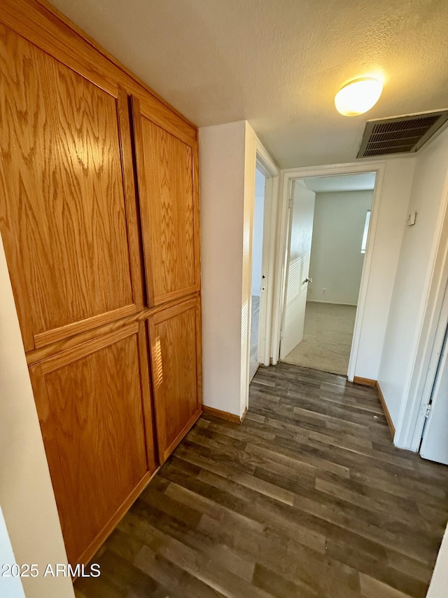 hallway featuring a textured ceiling and dark wood-type flooring