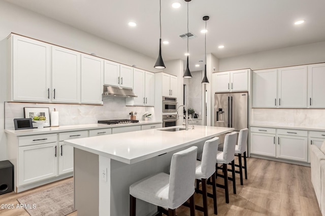 kitchen featuring a sink, stainless steel appliances, backsplash, a center island with sink, and recessed lighting