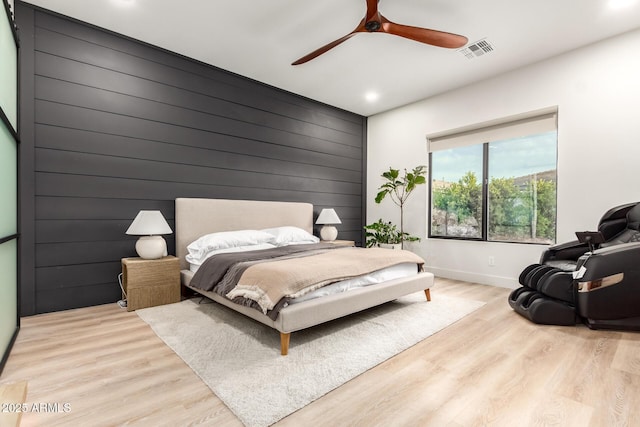 bedroom with baseboards, light wood-style floors, recessed lighting, wood walls, and a ceiling fan