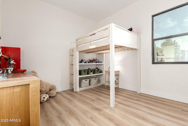 bedroom featuring light wood finished floors and baseboards
