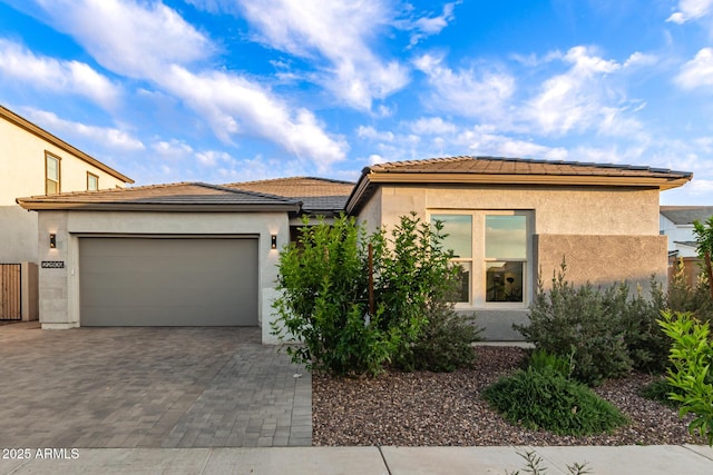 view of front of house featuring decorative driveway, a garage, stucco siding, and a tile roof