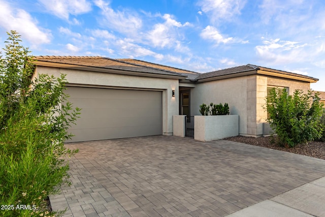 view of front of property featuring decorative driveway, a garage, stucco siding, and a tile roof