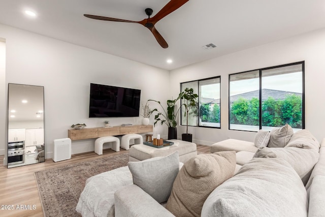 living room with a ceiling fan, light wood finished floors, recessed lighting, and baseboards