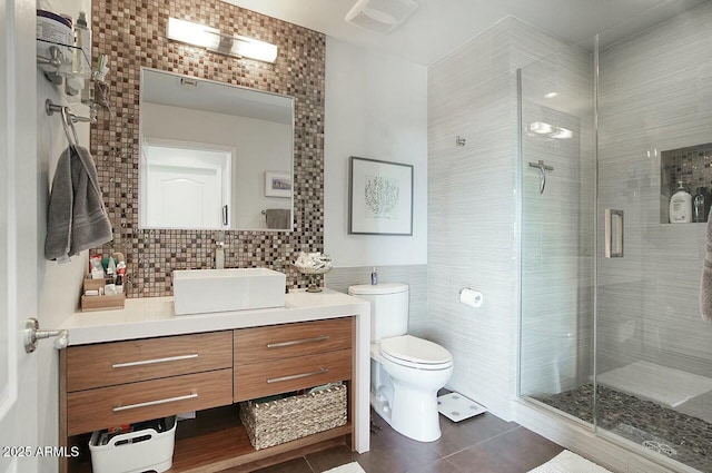 bathroom with visible vents, toilet, vanity, a stall shower, and tile walls