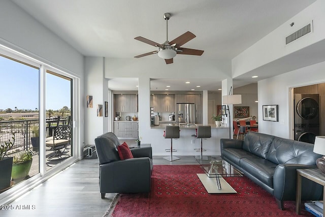 living area with visible vents, stacked washer and clothes dryer, wood finished floors, recessed lighting, and ceiling fan