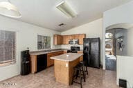 kitchen featuring a kitchen bar, a center island, black appliances, and vaulted ceiling