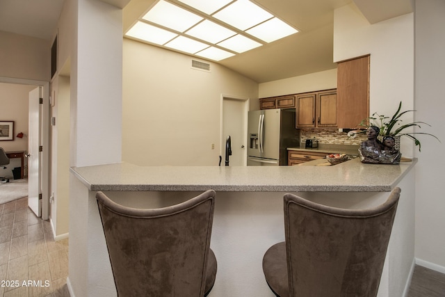 kitchen with sink, stainless steel fridge, tasteful backsplash, vaulted ceiling, and kitchen peninsula