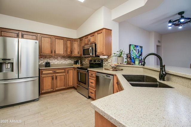 kitchen with sink, decorative backsplash, kitchen peninsula, and appliances with stainless steel finishes