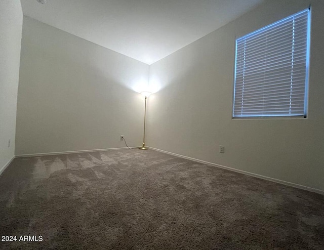 carpeted spare room with vaulted ceiling