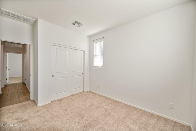 unfurnished bedroom with a closet and light carpet