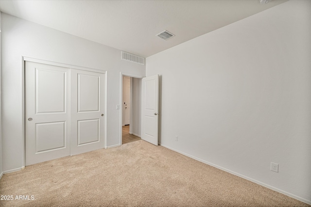 unfurnished bedroom featuring light colored carpet and a closet