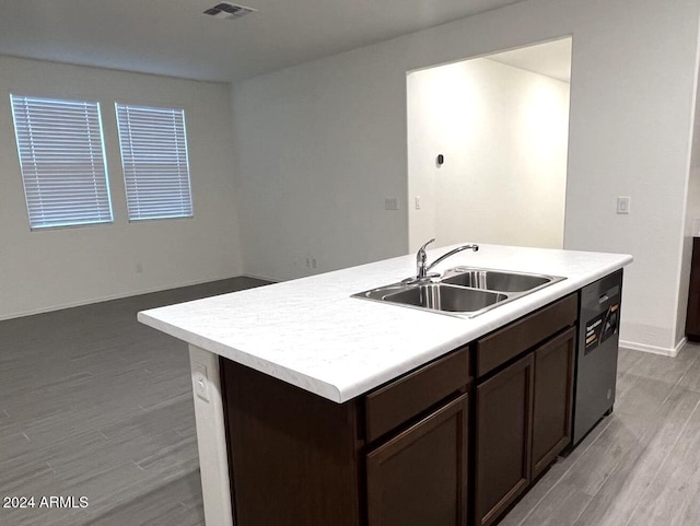 kitchen with sink, light hardwood / wood-style flooring, dishwasher, a kitchen island with sink, and dark brown cabinets