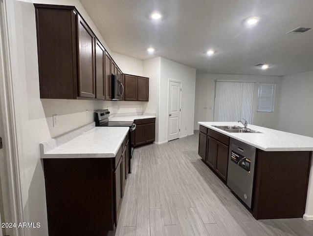 kitchen featuring dark brown cabinetry, sink, a center island with sink, stainless steel appliances, and light hardwood / wood-style floors