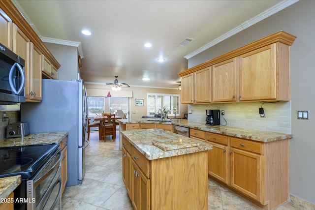 kitchen with appliances with stainless steel finishes, a kitchen island, ornamental molding, kitchen peninsula, and ceiling fan