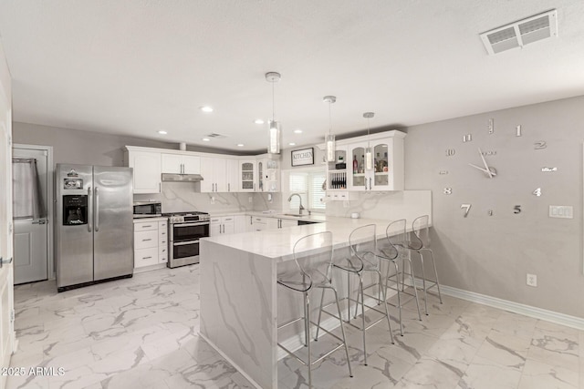 kitchen featuring white cabinetry, a kitchen breakfast bar, kitchen peninsula, pendant lighting, and stainless steel appliances