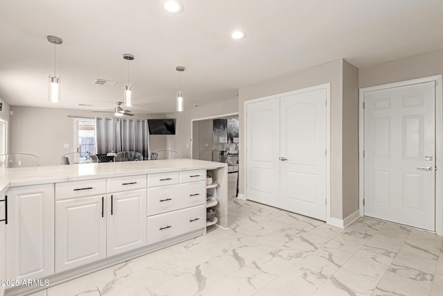 kitchen featuring light stone counters, pendant lighting, and white cabinets