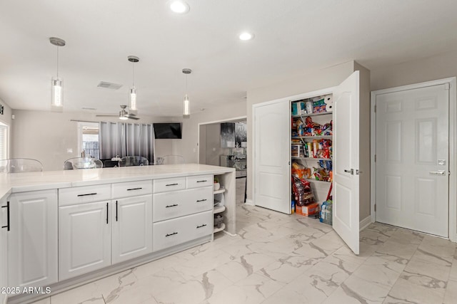 kitchen featuring light stone counters, hanging light fixtures, and white cabinets