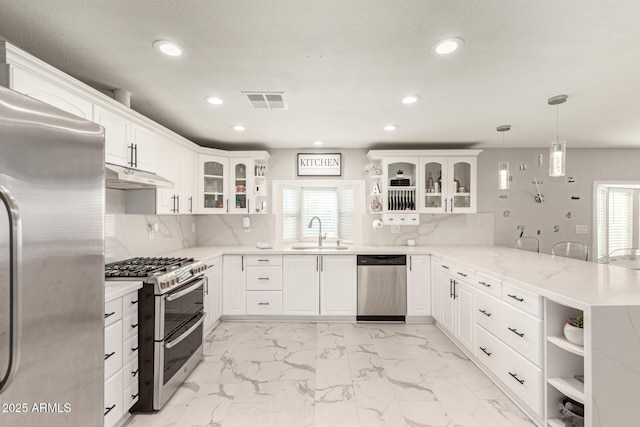 kitchen with kitchen peninsula, hanging light fixtures, appliances with stainless steel finishes, white cabinets, and decorative backsplash