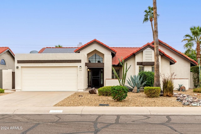 view of front of property with a garage and solar panels