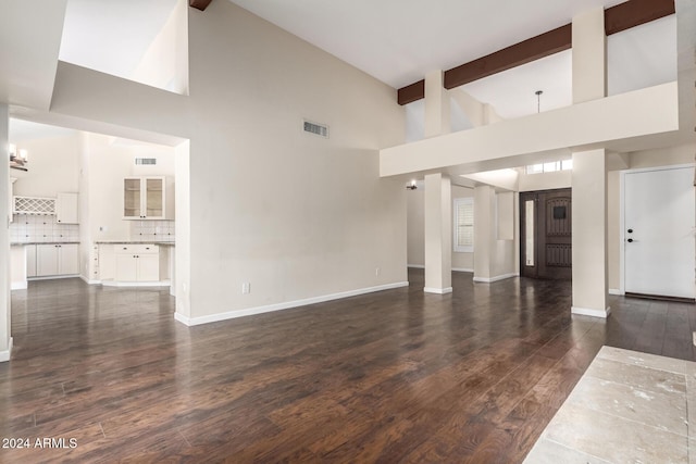 unfurnished living room with beamed ceiling, dark hardwood / wood-style floors, and high vaulted ceiling