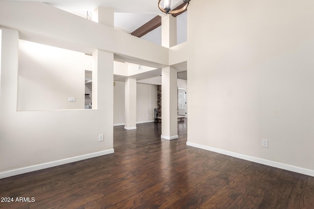 spare room with high vaulted ceiling and dark wood-type flooring