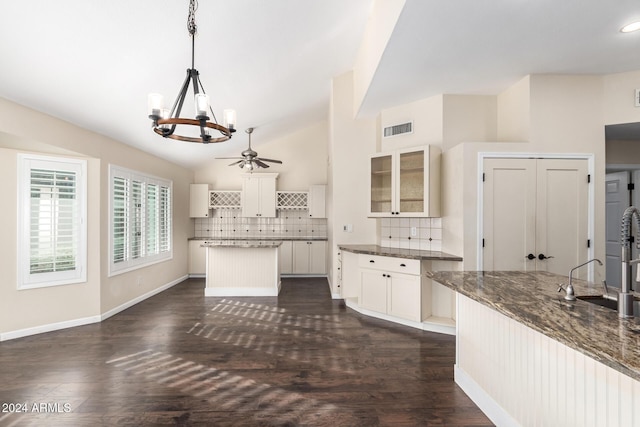 kitchen with sink, hanging light fixtures, vaulted ceiling, decorative backsplash, and white cabinets