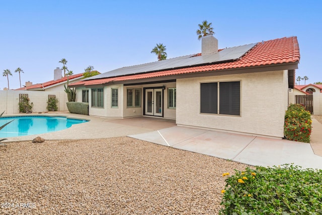 rear view of house with french doors, a fenced in pool, and a patio area