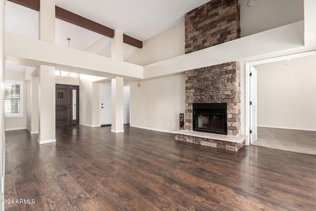 unfurnished living room featuring beamed ceiling, a fireplace, a towering ceiling, and dark hardwood / wood-style floors