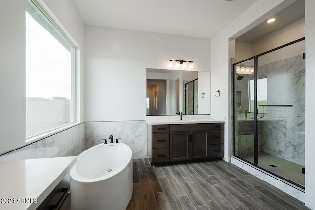 bathroom featuring independent shower and bath, tile walls, and vanity